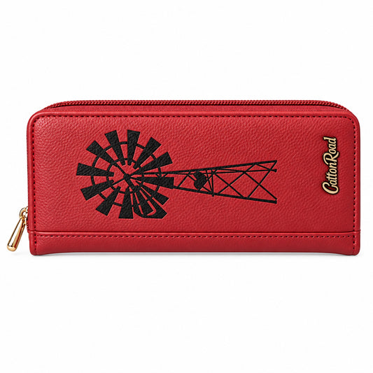 A red textured leather zip-around wallet featuring a black embossed windmill and tower graphic, a gold zipper pull, and the brand name 'Cotton Road' printed in gold on the right side, set against a solid black background.