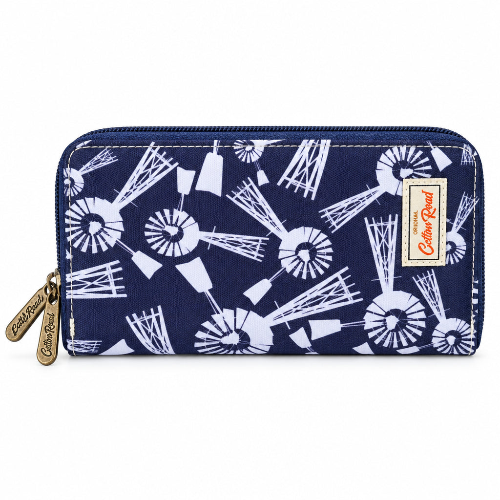 A zip-around wallet with a dark purple background and a white mid-century modern pattern of stylized windmills and geometric shapes. It features a gold-tone zipper pull with 'Color Road' branding and a matching fabric brand patch on the right side.