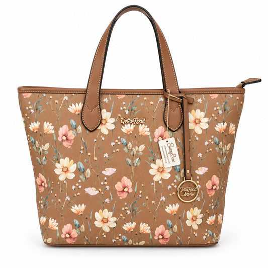 A brown tote bag with a floral print, featuring brown leather handles and a hanging tag, displayed on a white shelf.