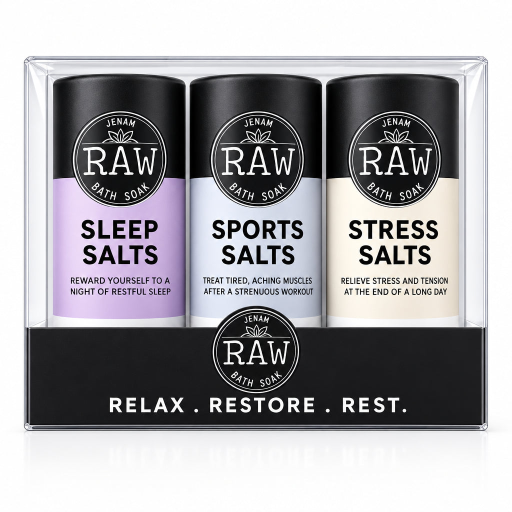 A set of three Jenam RAW Bath Soaks in a clear plastic clamshell package with a black cardboard insert. The three cylindrical bottles have black caps and bases, with lavender, light blue, and off-white labels for Sleep Salts, Sports Salts, and Stress Salts.