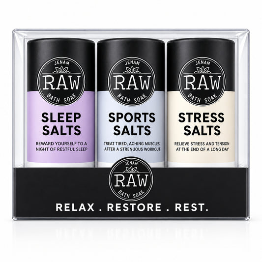 A set of three Jenam RAW Bath Soaks in a clear plastic clamshell package with a black cardboard insert. The three cylindrical bottles have black caps and bases, with lavender, light blue, and off-white labels for Sleep Salts, Sports Salts, and Stress Salts.