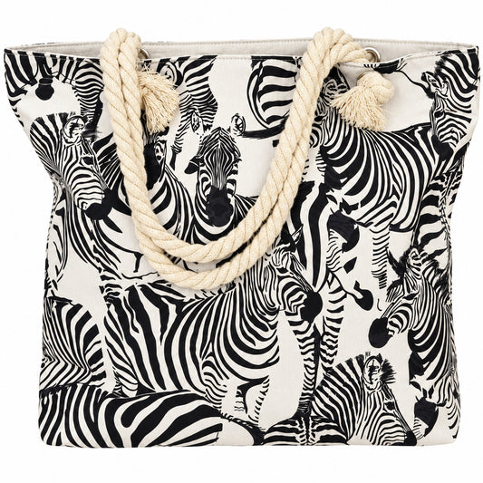A tote bag featuring an all-over black and white zebra print on a light beige background, with thick cream-colored rope handles and tassel ends.